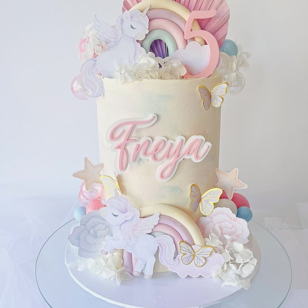 Colorful unicorn-themed birthday cake featuring a double layered cake topper.